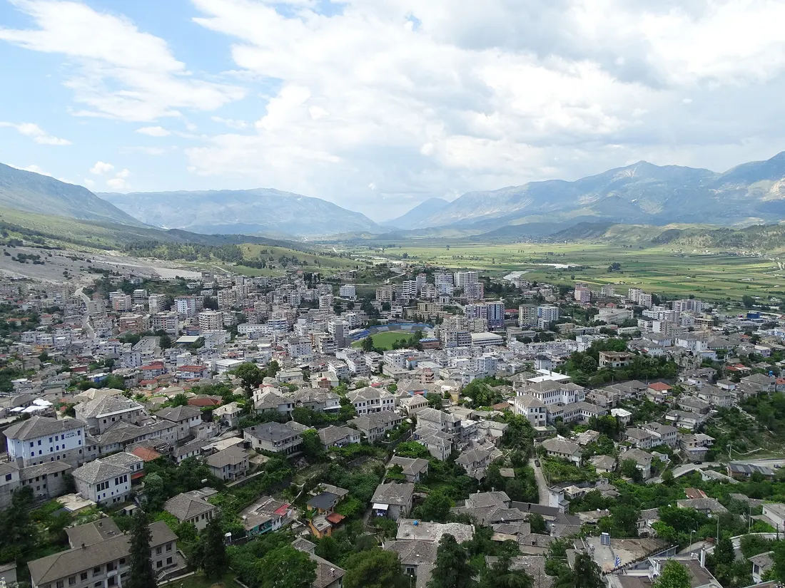 Grey-roofed houses of Gjirokastër spread across the valley below the castle