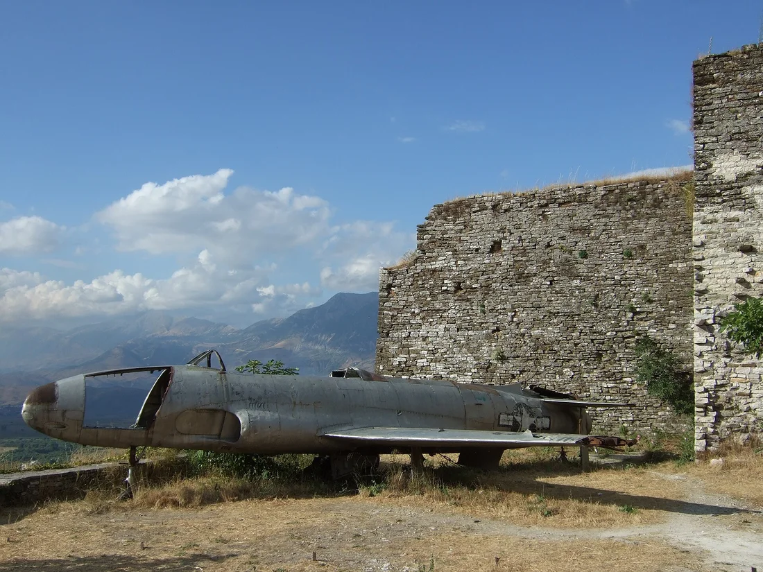 Silver US-marked Lockheed T-33 jet on display beside a stone castle wall