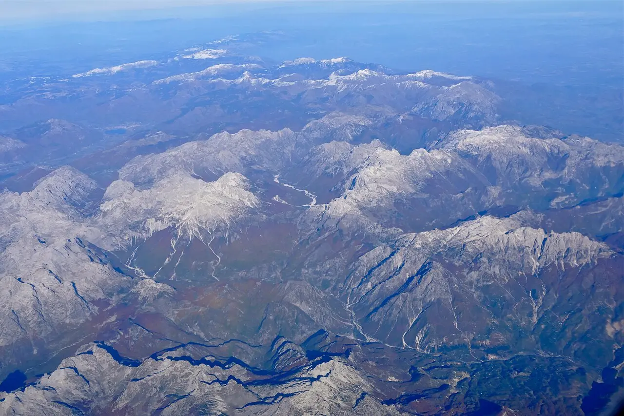 Jagged limestone peaks of the Accursed Mountains rising above forested slopes