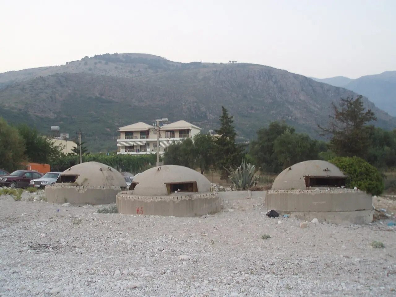 Three domed concrete bunkers from the communist era on stony ground below the hills near Himara
