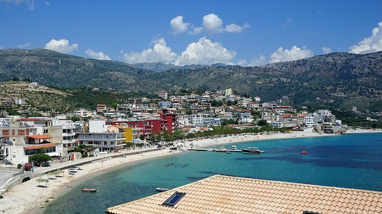 Himara town and its turquoise bay seen from above, houses climbing the hillside below the Ceraunian Mountains