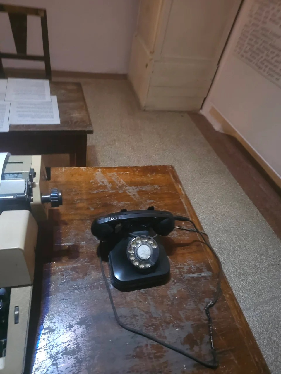 A black rotary telephone on a worn wooden office desk inside the House of Leaves museum