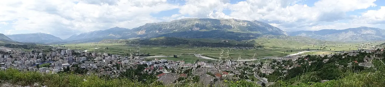 Panorama of Gjirokaster town spread across the Drino valley below a long mountain ridge