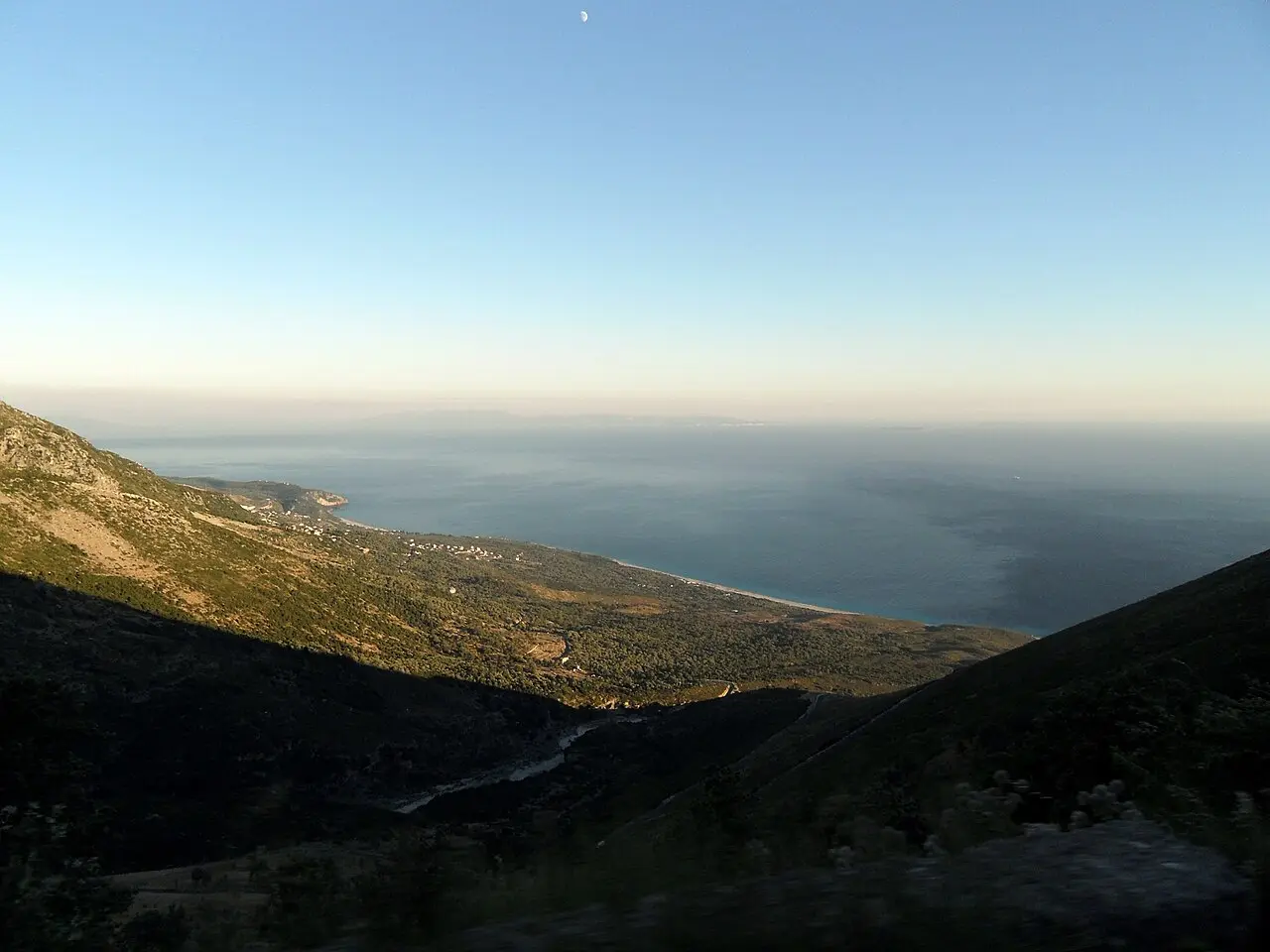 A bend on the SH8 coastal road with the sea and Riviera hills beyond