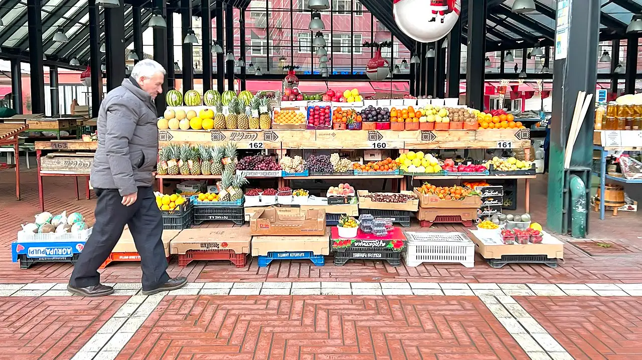 A fruit stand in Tirana with boxes of fresh produce and local prices displayed at the counter