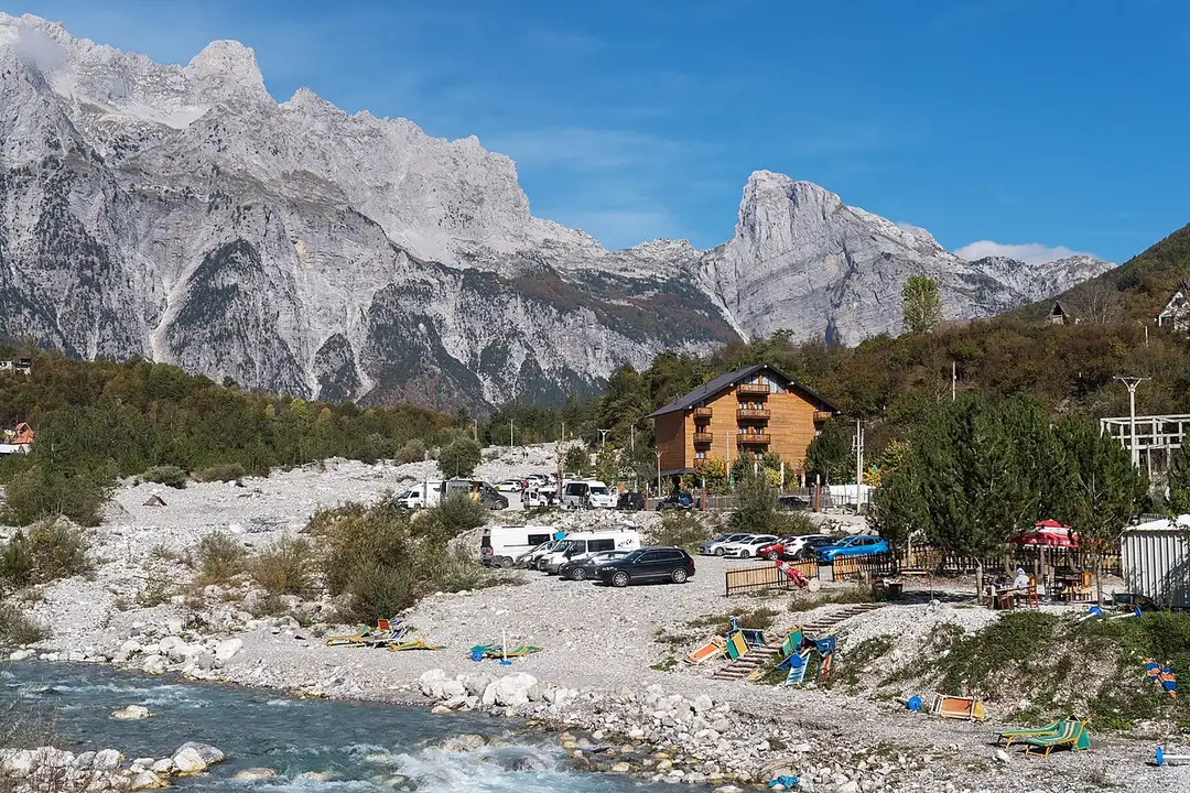 Stone houses and a church scattered across the green Theth valley under the Accursed Mountains