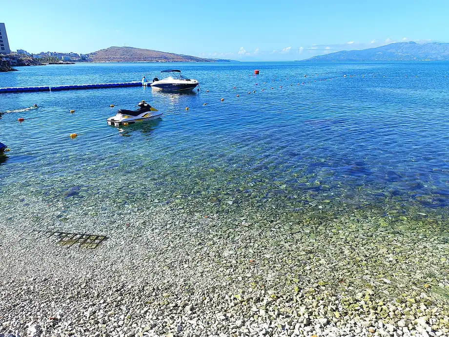 The pebbly town beach of Saranda along the seafront with the town rising behind