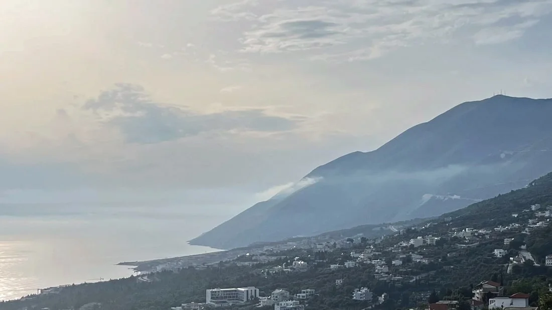 Coastline and mountain slopes above Dhërmi seen from the coast road in morning haze
