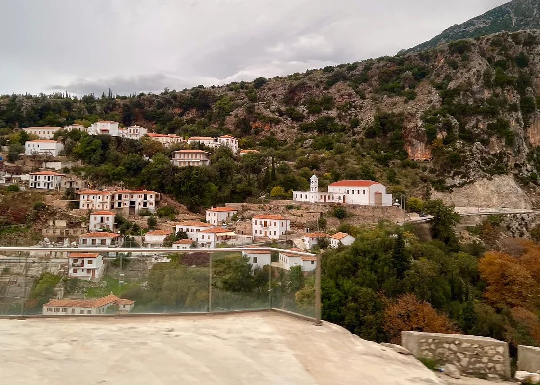 White village houses and a church on the green slope above Dhërmi