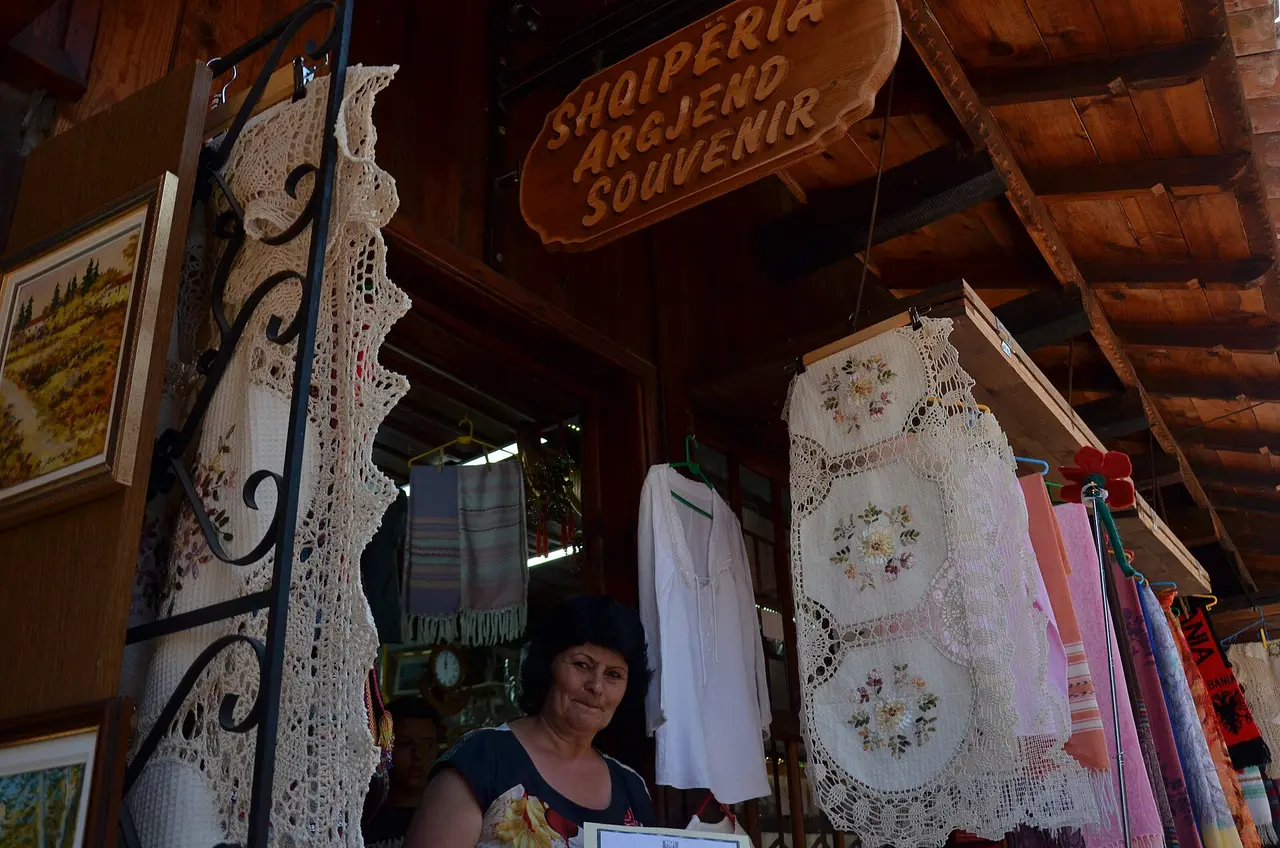 Hand-crocheted lace, embroidered doilies and framed pictures hanging outside a souvenir shop in the Kruja bazaar