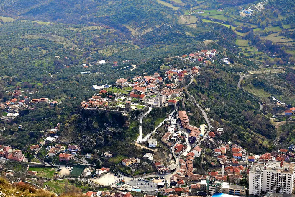 An aerial view of the Kruja castle promontory and the old town clustered on the ridge, the bazaar lane and houses winding around the fortress rock