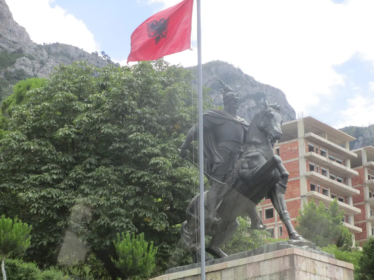 The bronze equestrian statue of Skanderbeg on horseback below the Albanian flag and Mount Krujë