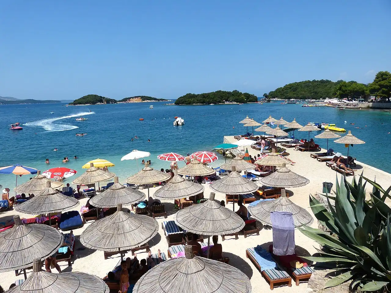 A small cove at Ksamil lined with sun-loungers and umbrellas beside turquoise water