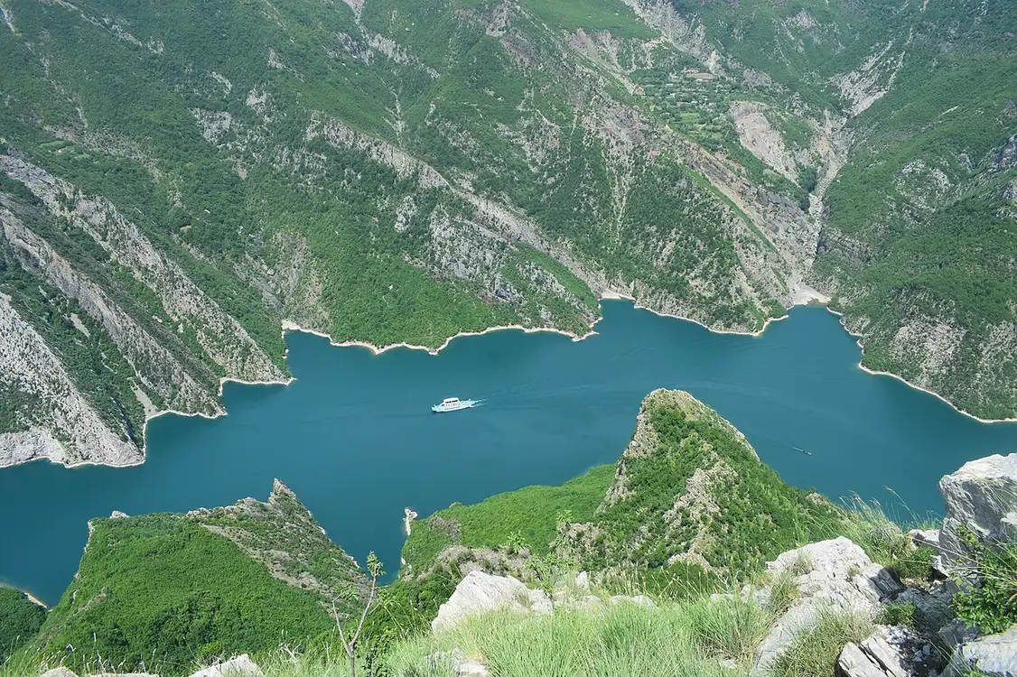 The Lake Koman ferry crossing a narrow emerald reservoir hemmed in by steep green mountains in northern Albania