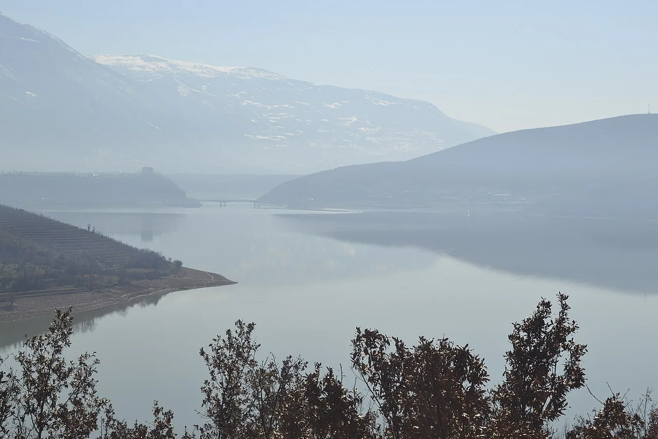 The wider Fierza reservoir at the northeastern end of the Koman ferry route, with mountains reflected in calm water