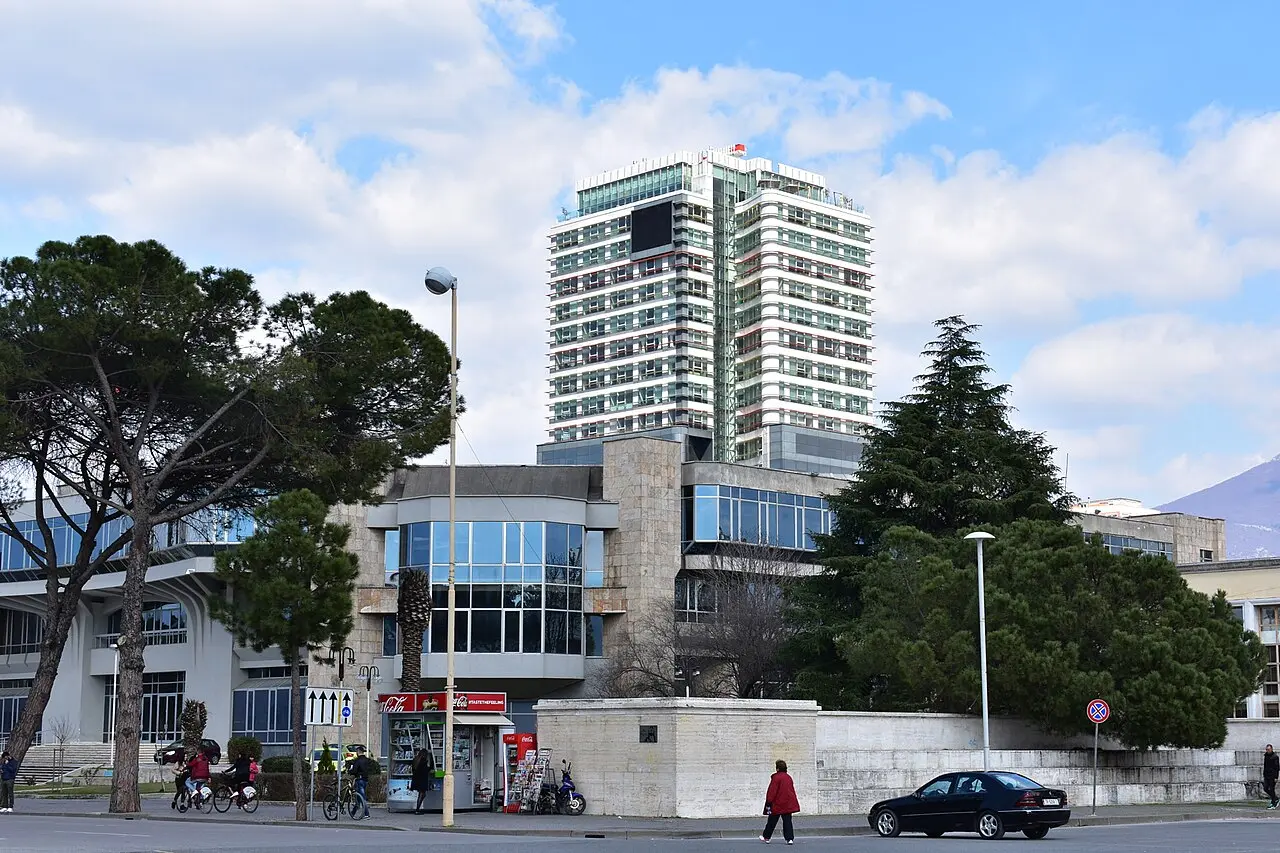 A daytime view over the rooftops and boulevards of Tirana from a hillside university terrace