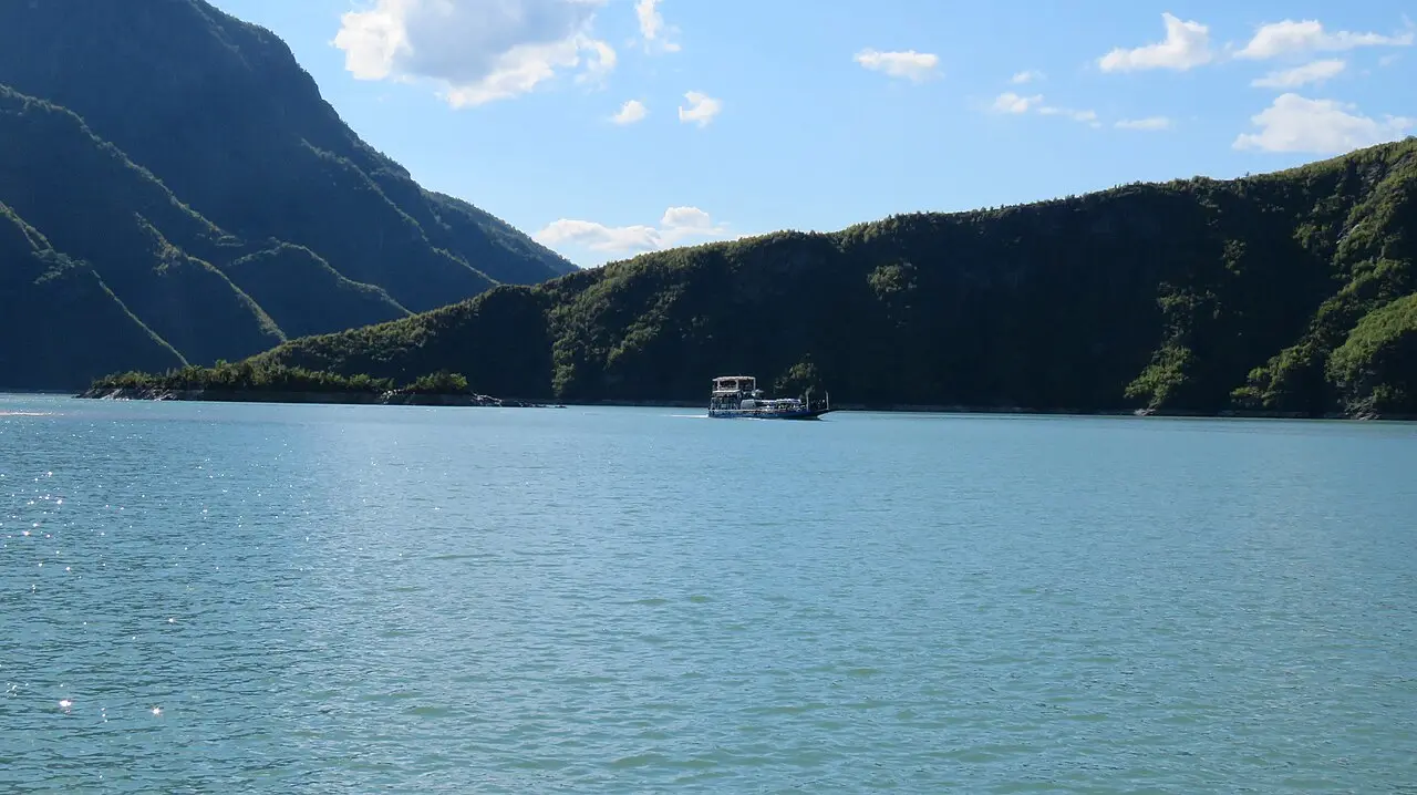 The Komani Lake ferry crossing the turquoise reservoir between steep green mountains