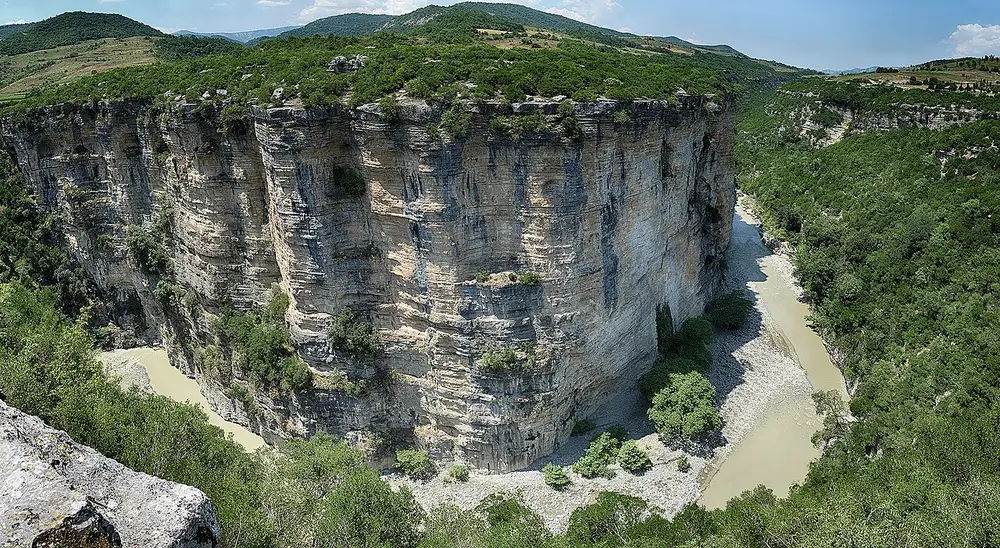 Wide bend of Osumi Canyon with a cliff face and the pale Osum river below