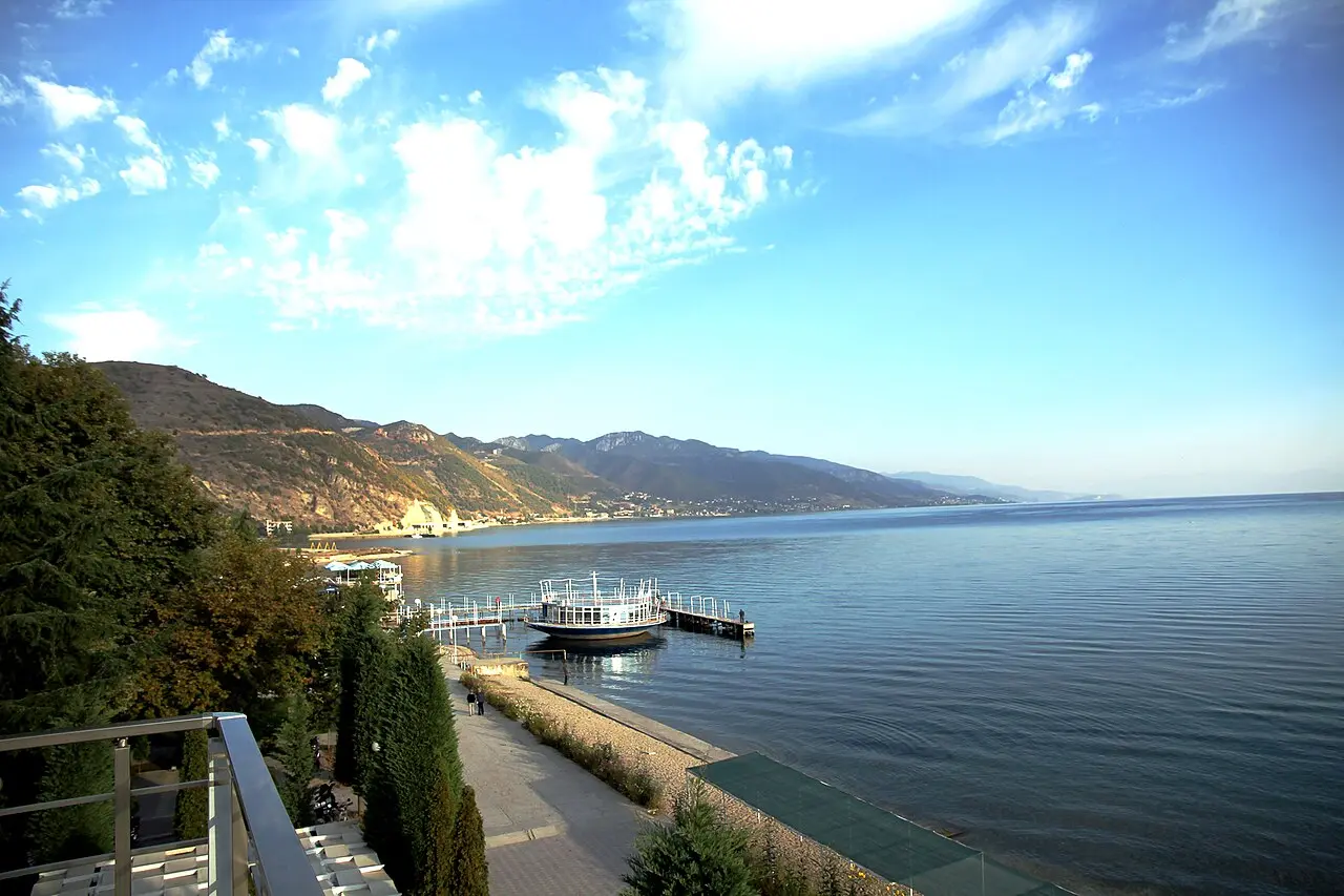 A pier and swimming platform on the calm blue water of Lake Ohrid at Pogradec, mountains beyond