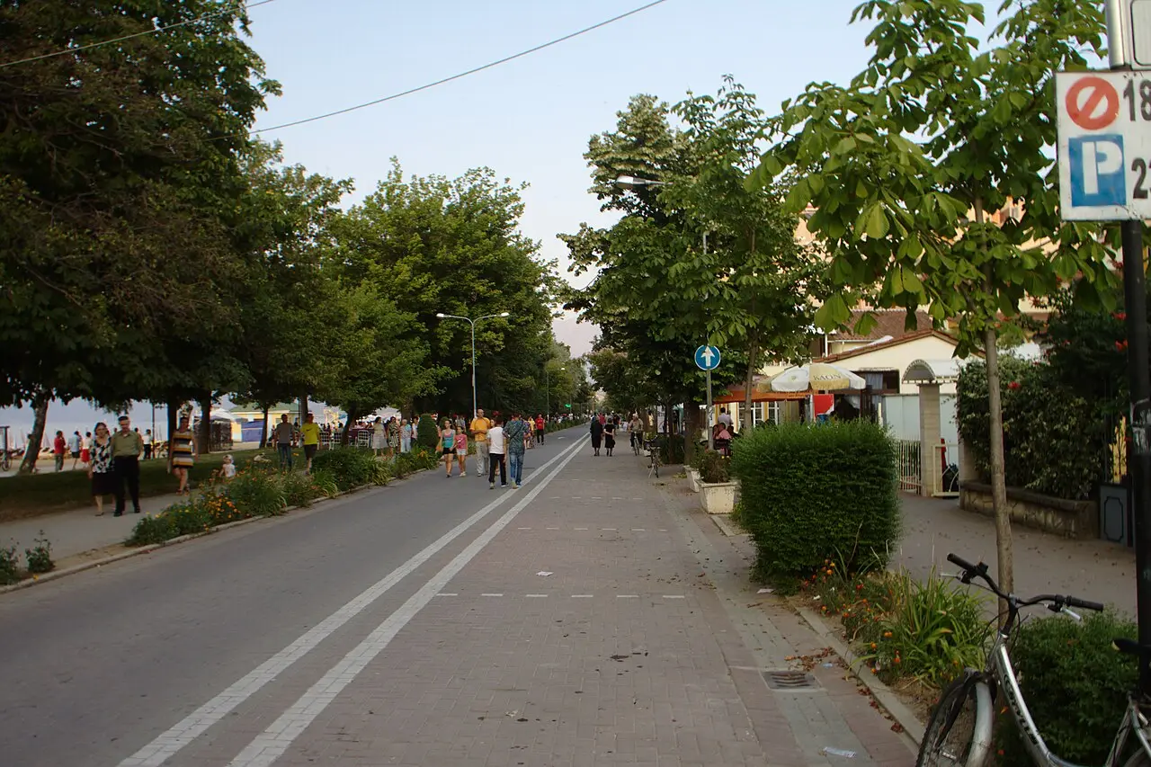 The wide tree-lined pedestrian promenade in Pogradec with people strolling in the evening