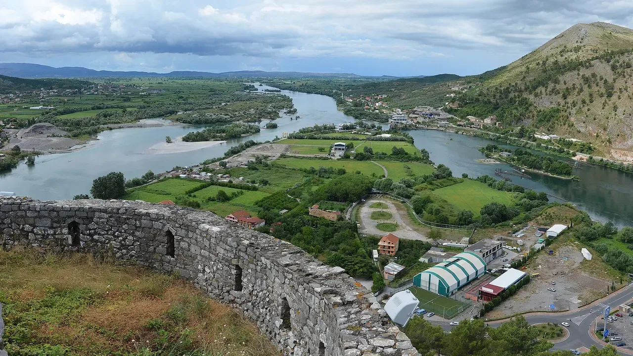 A stretch of Rozafa Castle wall with arrow slits in the foreground and the river plain of Shkodra spreading out below