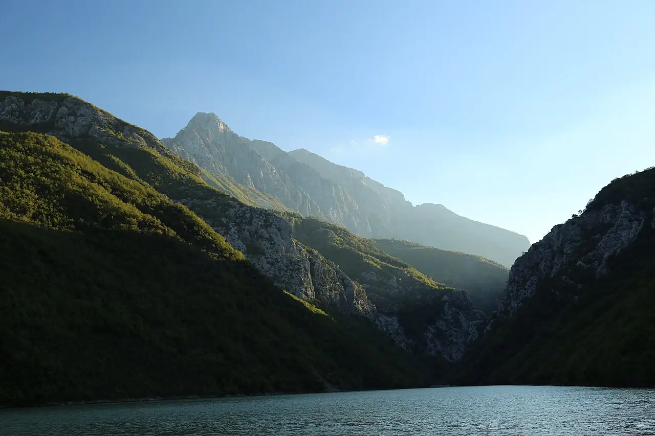 Limestone and forest cliffs rising straight from the green water of Lake Koman