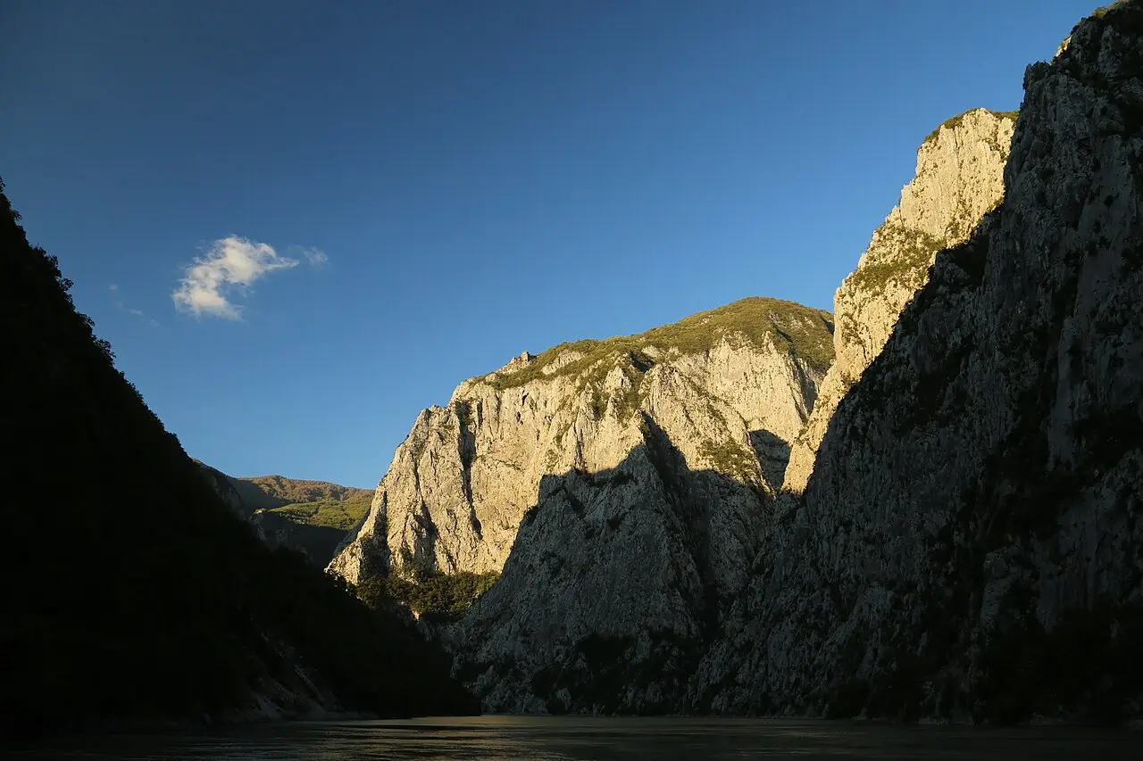 A small passenger boat on the narrow green reservoir of Lake Koman in the Albanian Alps
