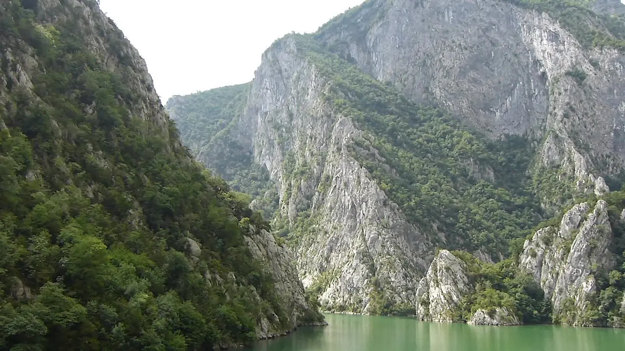 The Koman Lake ferry passing through a steep narrow gorge of green water