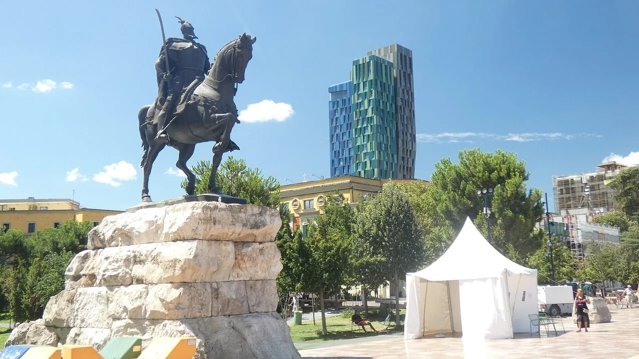 Bronze equestrian statue of Skanderbeg on a stone plinth in Tirana's Skanderbeg Square under a blue sky