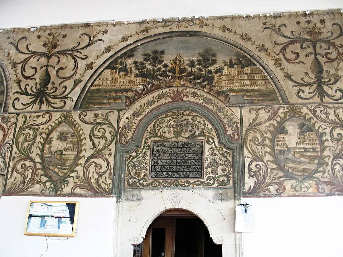 Painted portico of Et'hem Bey Mosque with arches, a wooden ceiling and frescoes