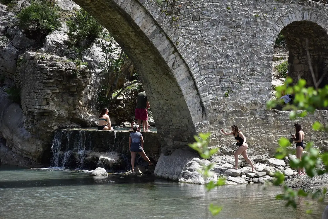 People bathing in the thermal pools under the arch of the old Kadiu Bridge on the Lengarica near Benje