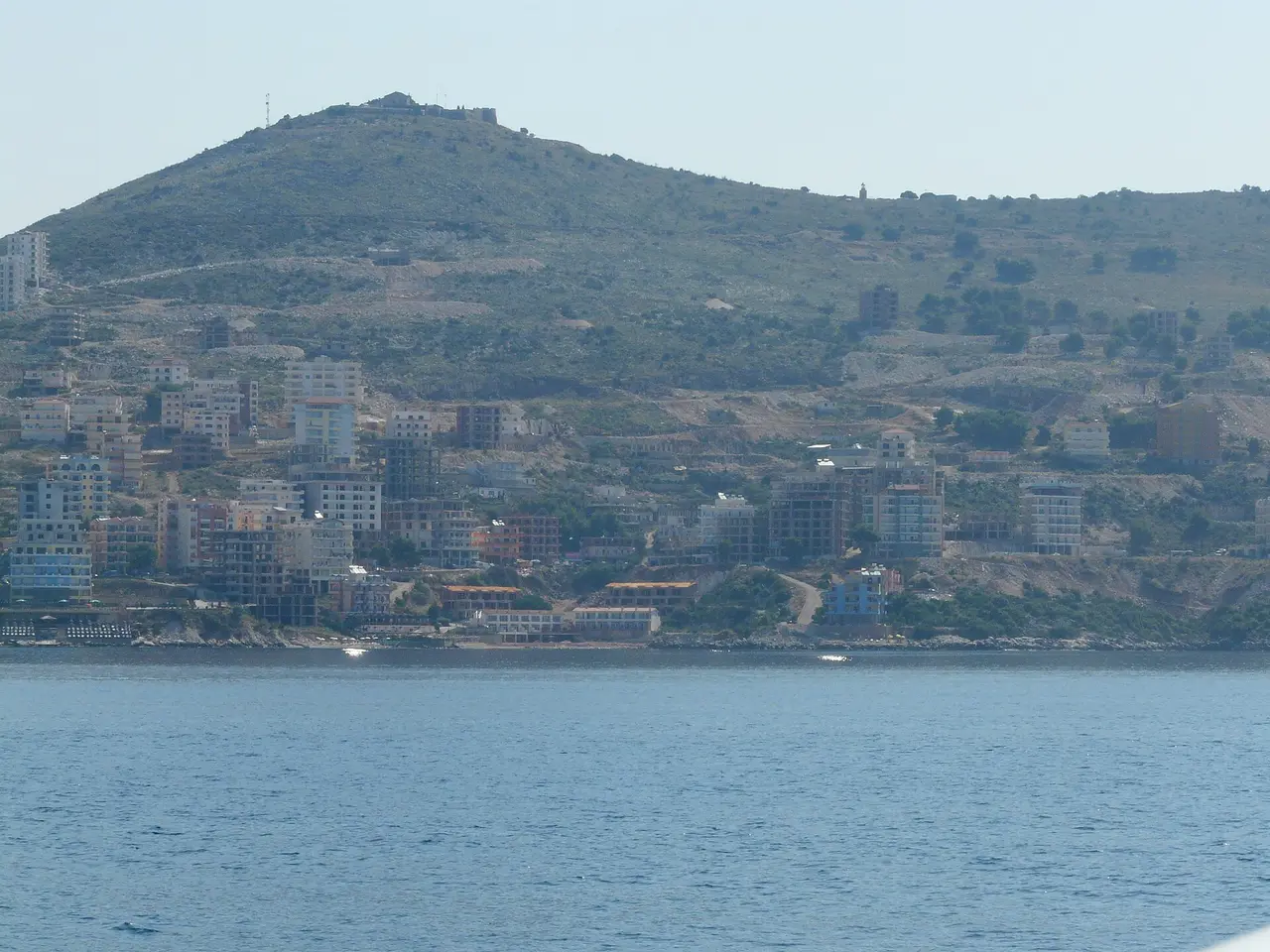 The town of Saranda climbing the hillside above the Ionian, with Lekursi Castle on the ridge, seen across the water
