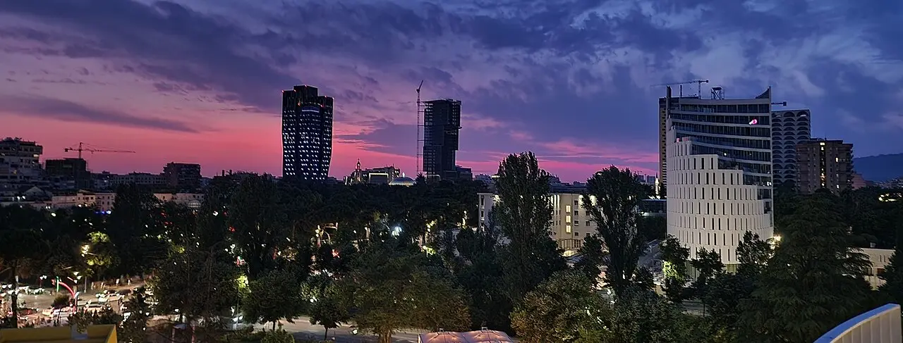 Tirana skyline at dusk with new towers under a pink and purple sky