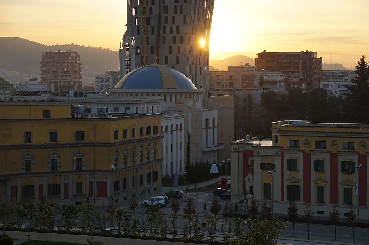 Golden-hour view over the colourful government buildings and cathedral dome in Tirana