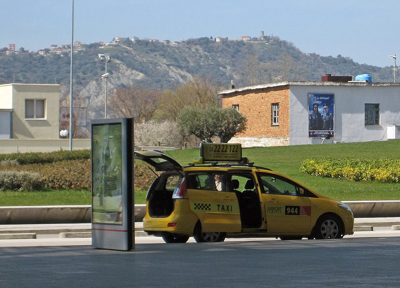 The hilltop village of Preza seen from the Rinas plain near Tirana airport, with green fields and a castle on the ridge