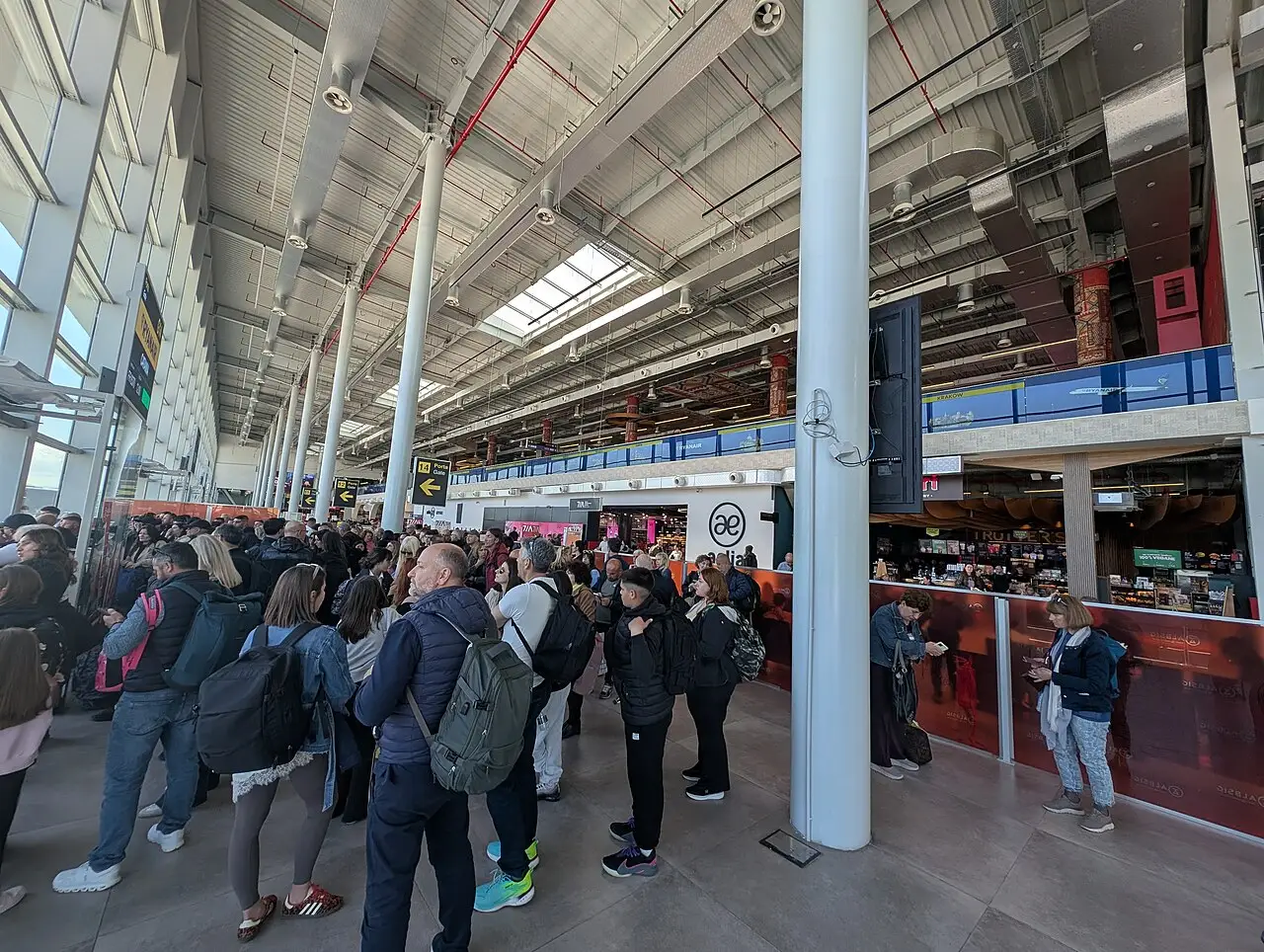 The busy departures hall inside Tirana International Airport with crowds of passengers under a high roof