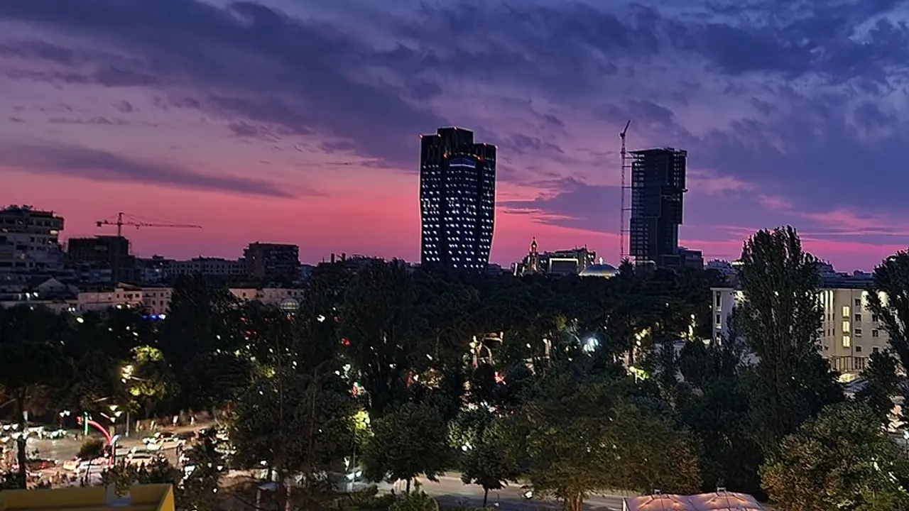Tirana skyline at dusk with lit towers above the Grand Park, near the Blloku district