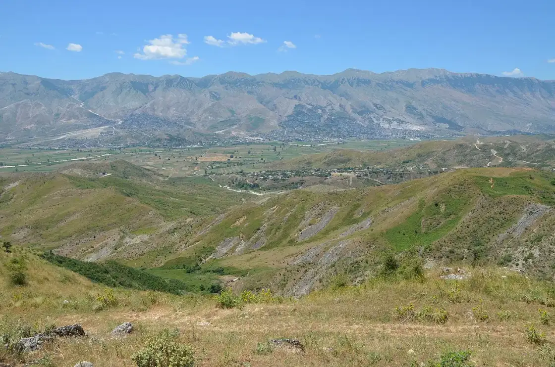 Rural Albanian road through green hills with mountains in the distance