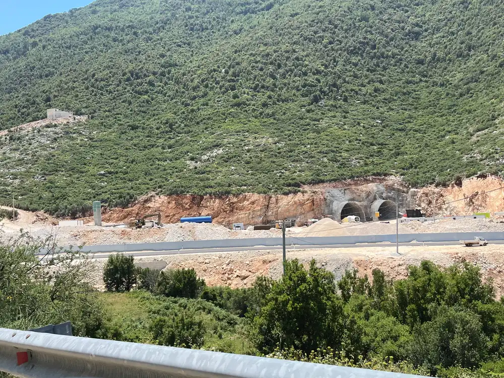 Construction of the Llogara Tunnel near Dukat, Albania in 2022, showing two unlined bores, excavators and site cabins before the road opened