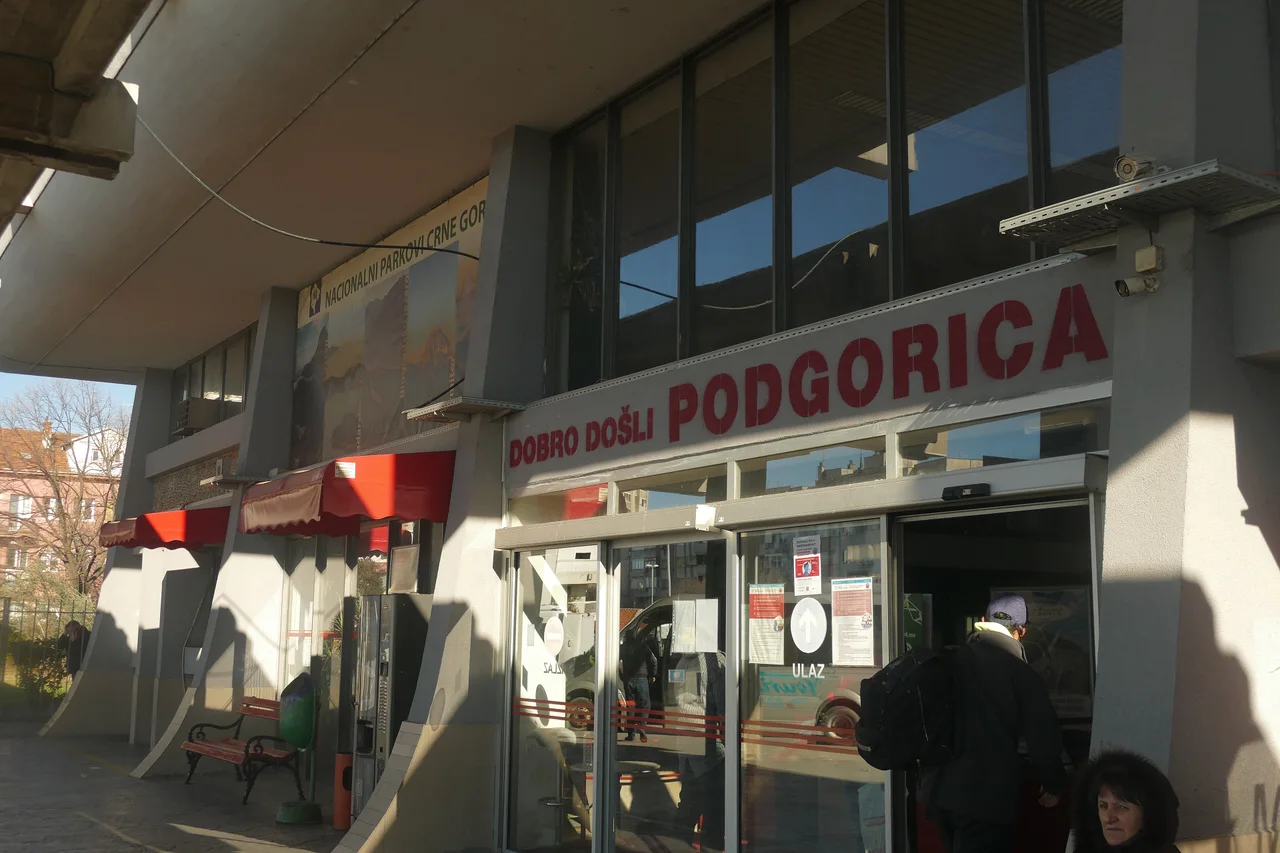 The entrance of Podgorica bus station with a red sign reading Dobro došli Podgorica and passengers walking in