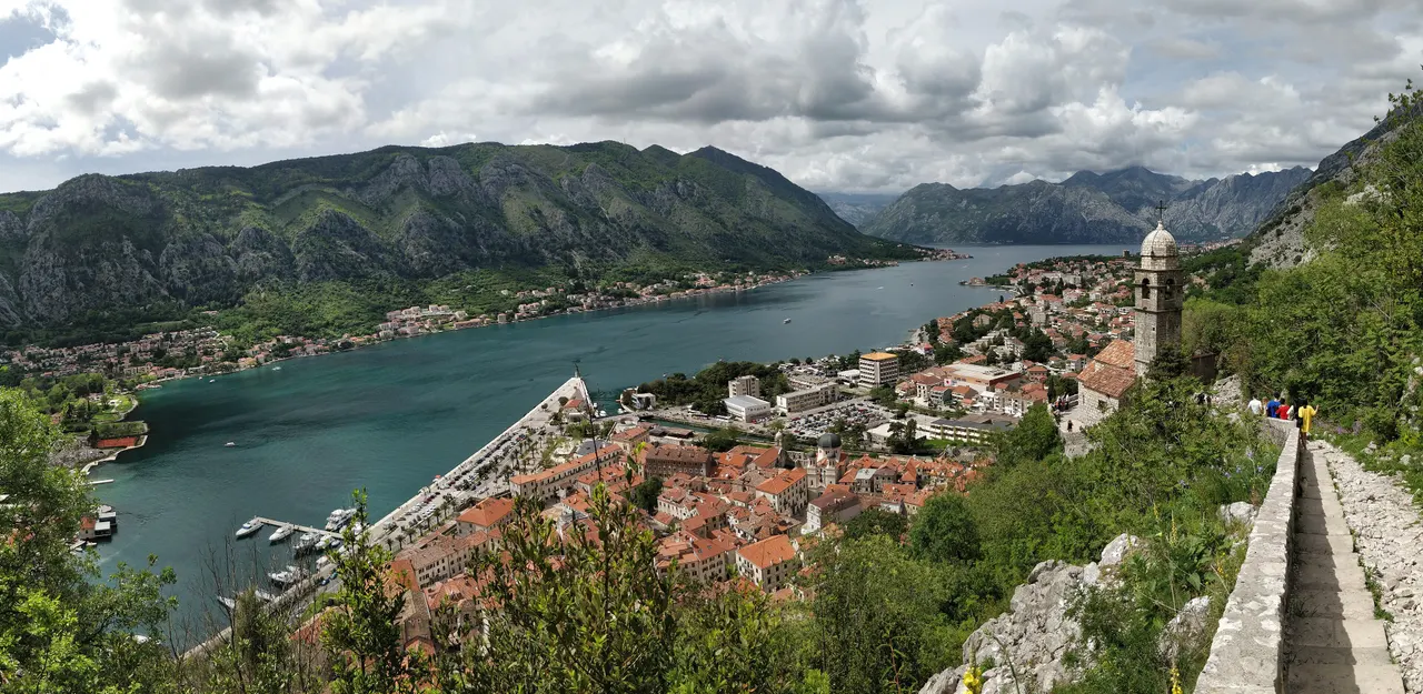 The Bay of Kotor and the terracotta roofs of Kotor Old Town seen from the fortress walls above, with mountains around the water