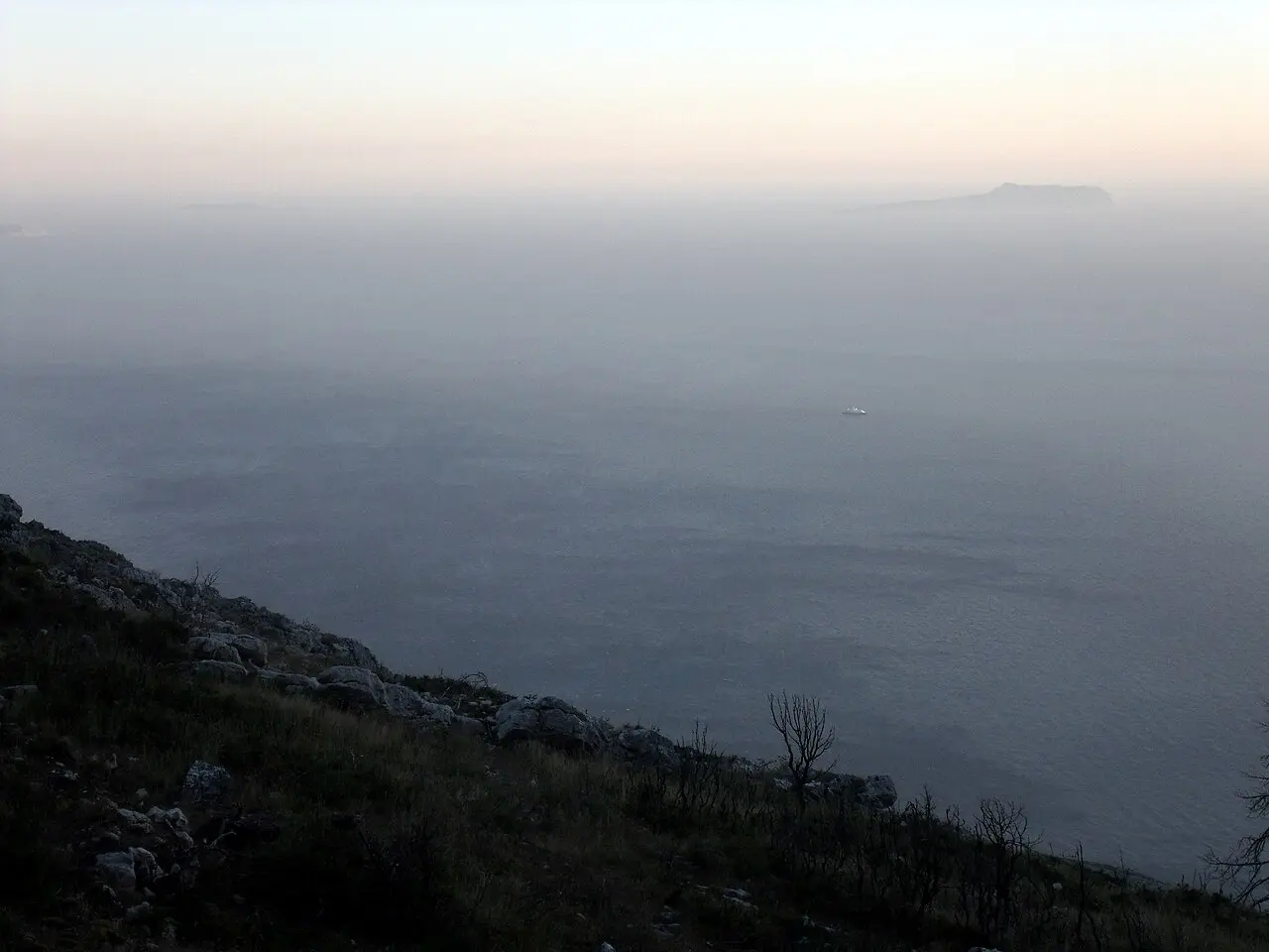 The SH8 coastal road winding along the Ionian Sea between Vlore and Sarande with bare hills and blue water