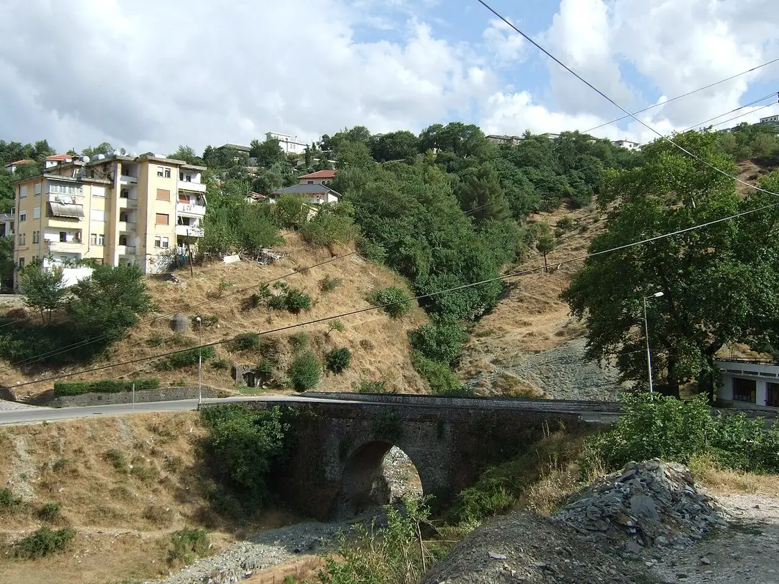 An old stone bridge below the town of Gjirokaster in southern Albania, with hillside houses behind