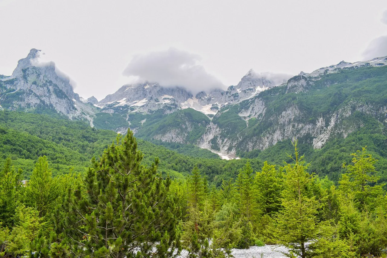 Wide green Valbona Valley floor with limestone peaks of the Albanian Alps rising on both sides