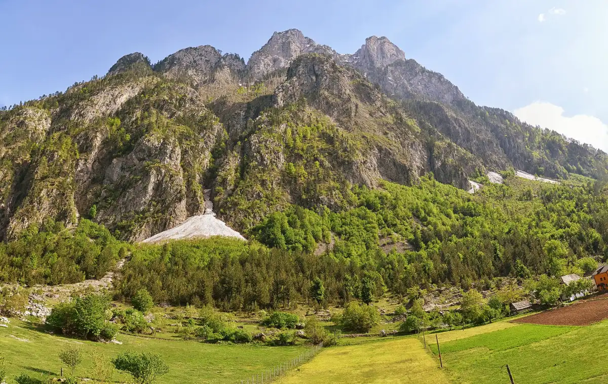 Sharp alpine peak rising above forested slopes in Valbonë