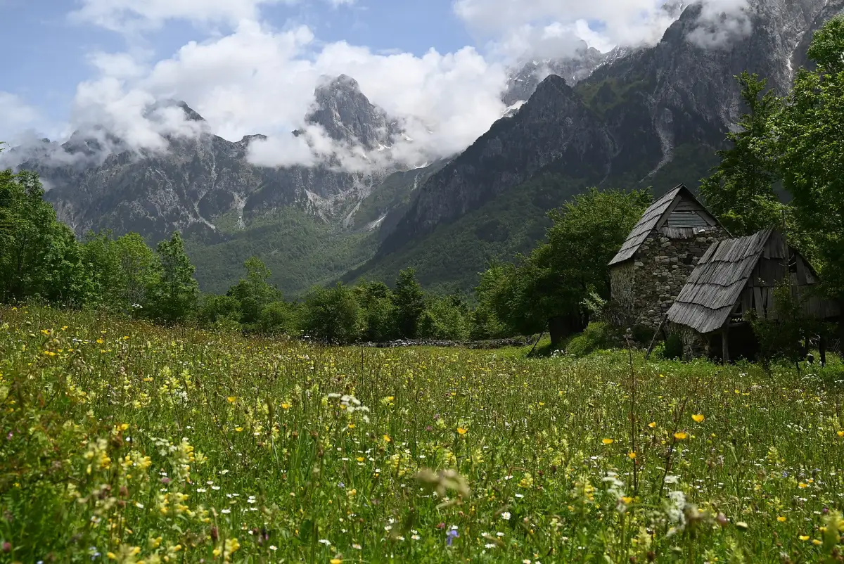 Stone houses and meadows at Rragam under steep Valbona peaks