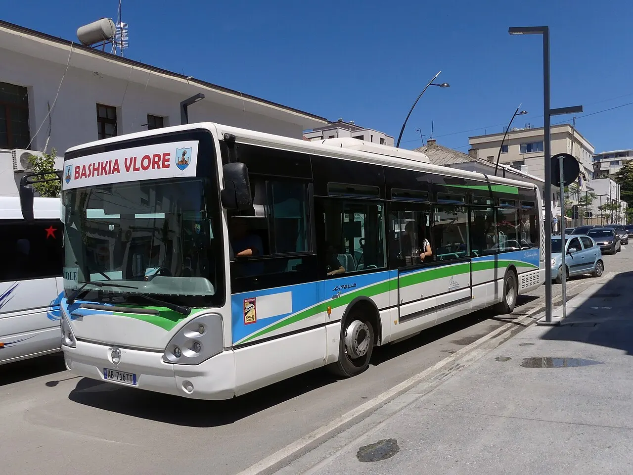 A white and green municipal bus marked Bashkia Vlore parked on a street in central Vlora, Albania