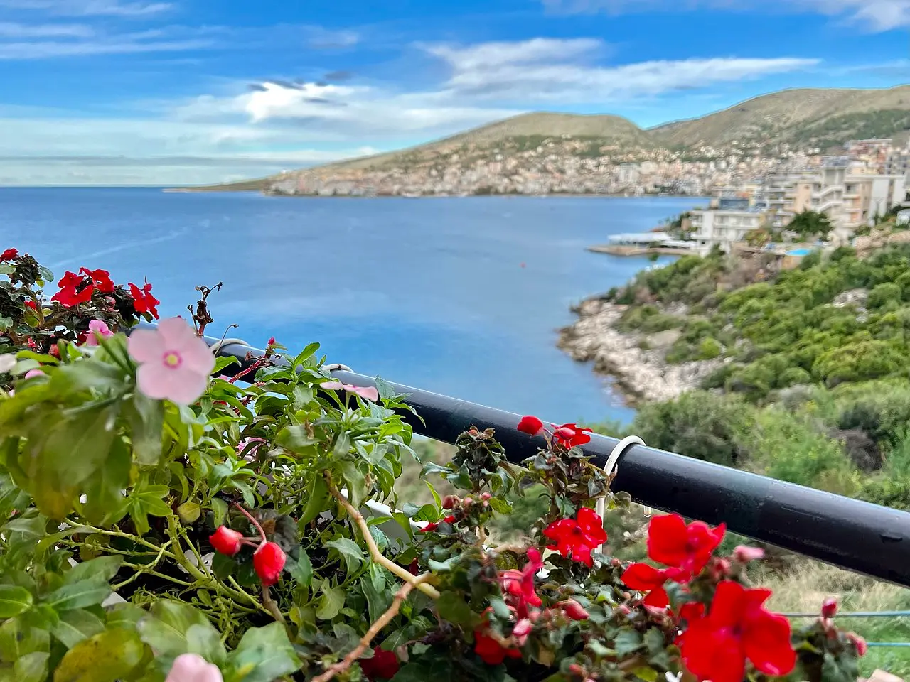 A Saranda balcony overlooking rooftops and the blue Ionian Sea toward the horizon