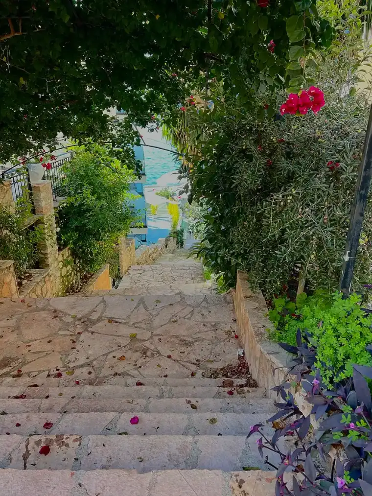 A steep flight of stairs climbing between buildings on the Saranda hillside