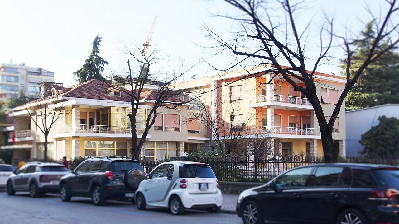 The Villa of Enver Hoxha on a leafy Blloku street, with parked cars along the roadside